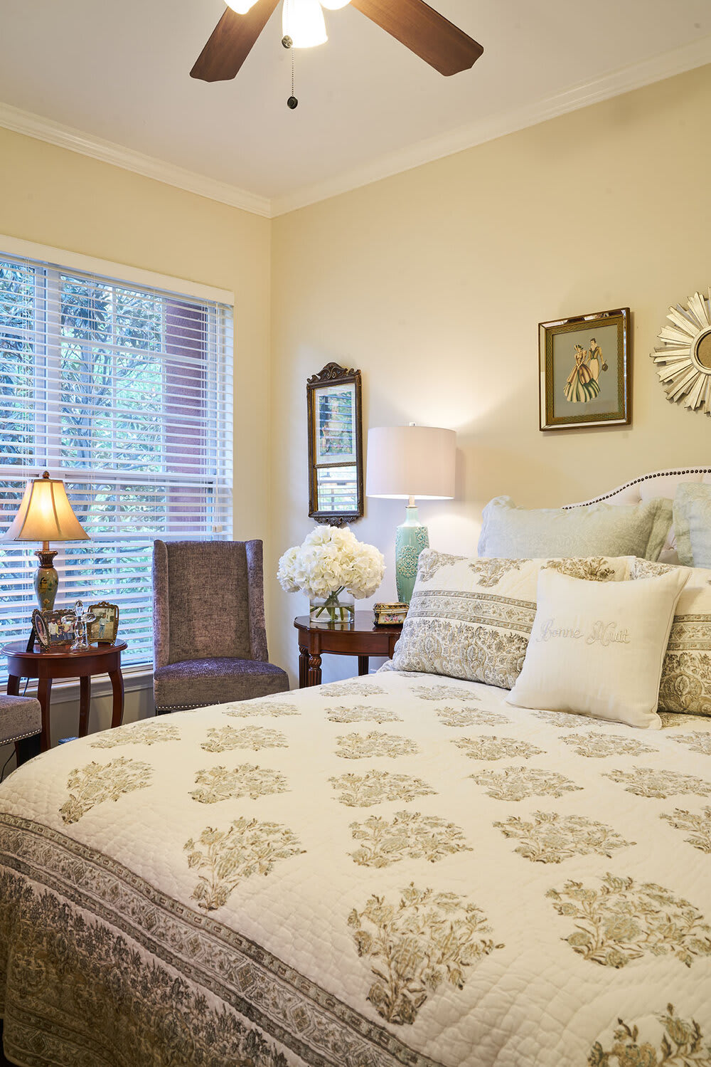 A cozy bedroom with elegant decor, featuring a bed with patterned bedding and soft lighting from lamps.