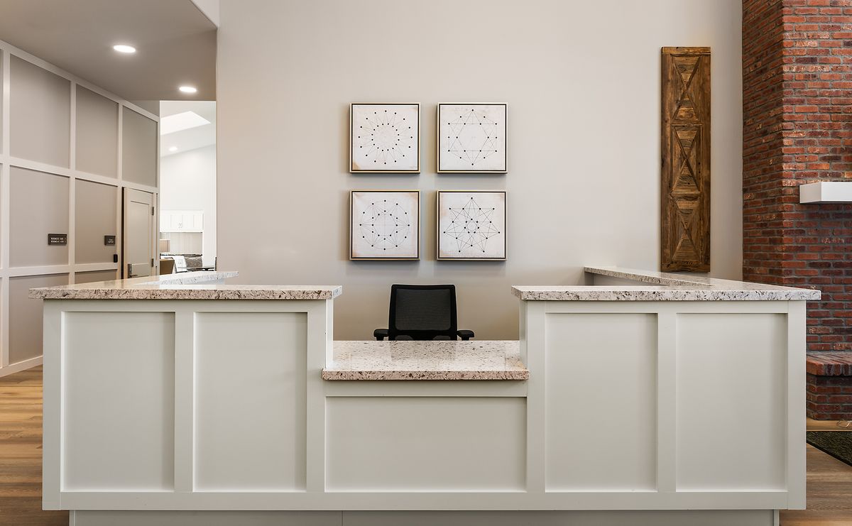 A modern reception desk with artwork on the wall and a computer on the counter.