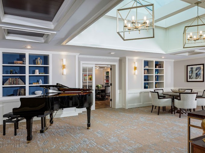 A modern interior room featuring a grand piano, elegant chandelier, and built-in shelves.