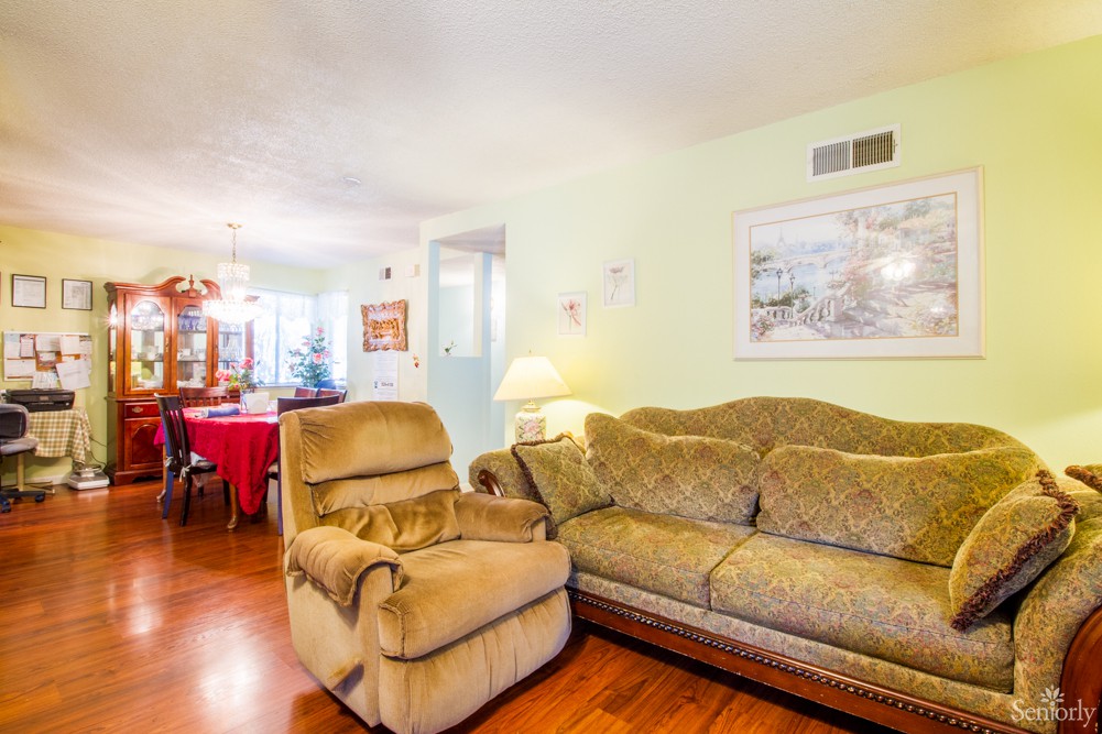 Cozy living room with a sofa and recliner, featuring wood flooring and wall art.
