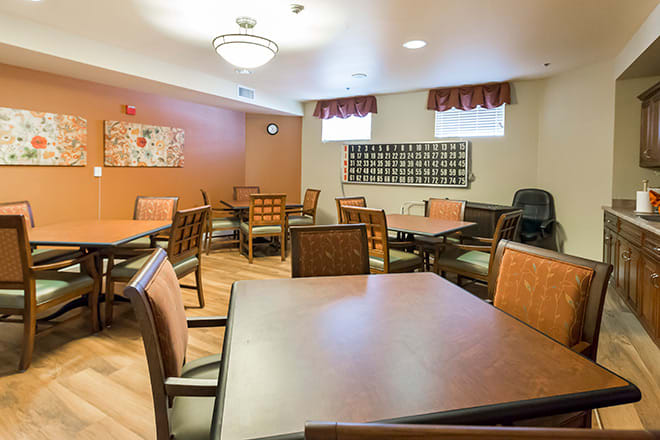 A community dining room with multiple tables and chairs arranged for gatherings.