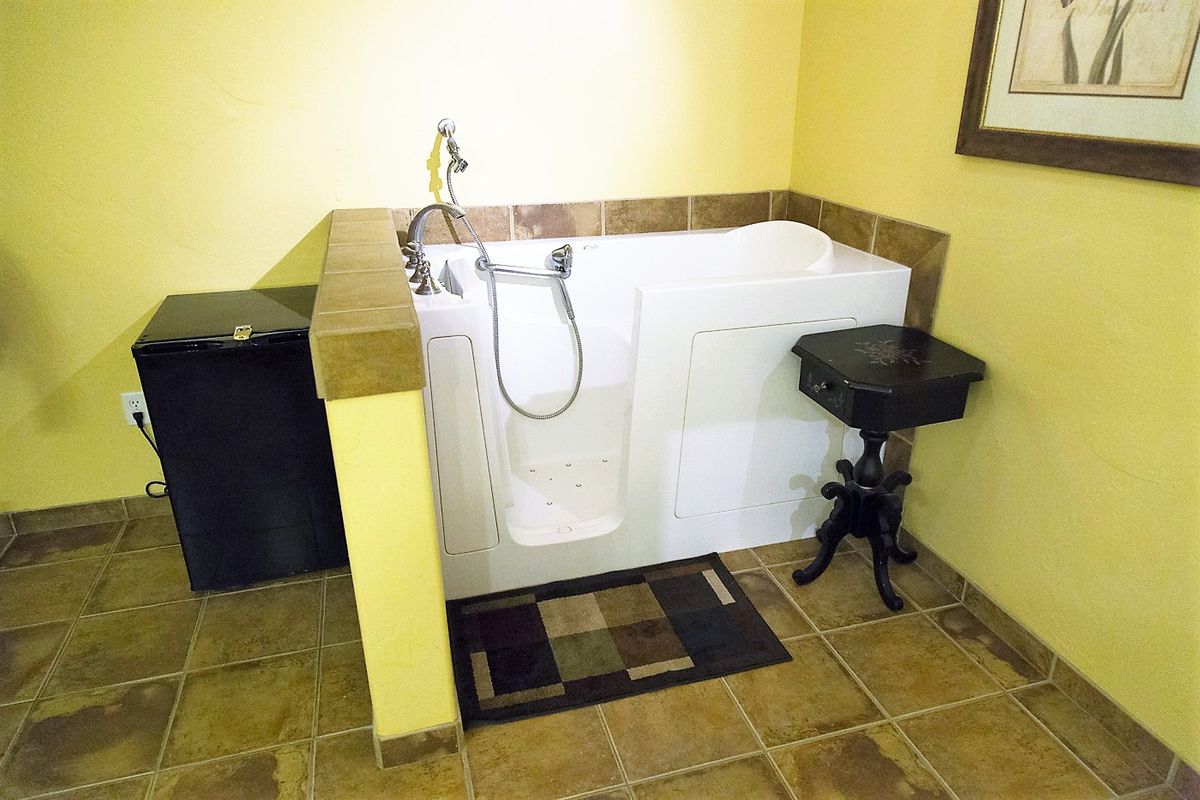 A bathroom featuring a walk-in bathtub with tiled surroundings.