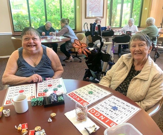 A group of seniors happily playing bingo together in a bright, communal space.
