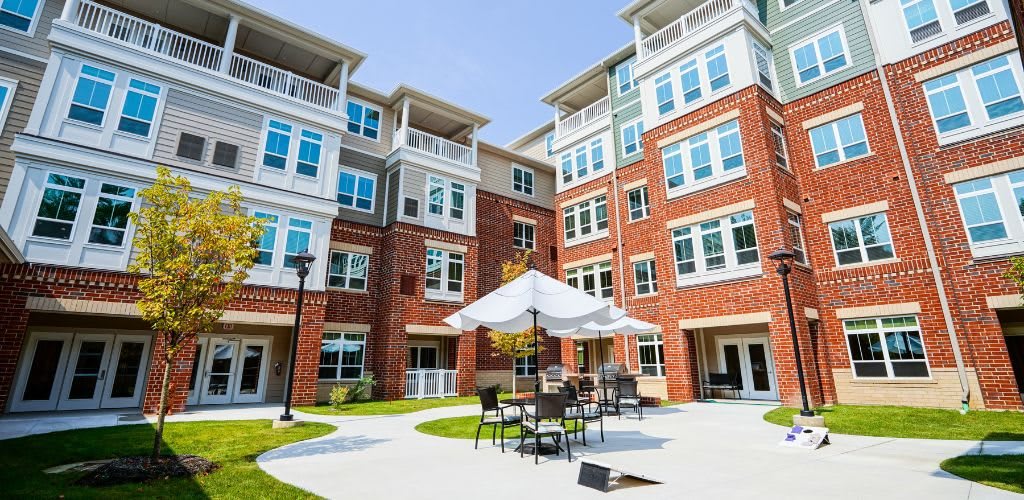 A modern apartment building with outdoor seating area on a sunny day.