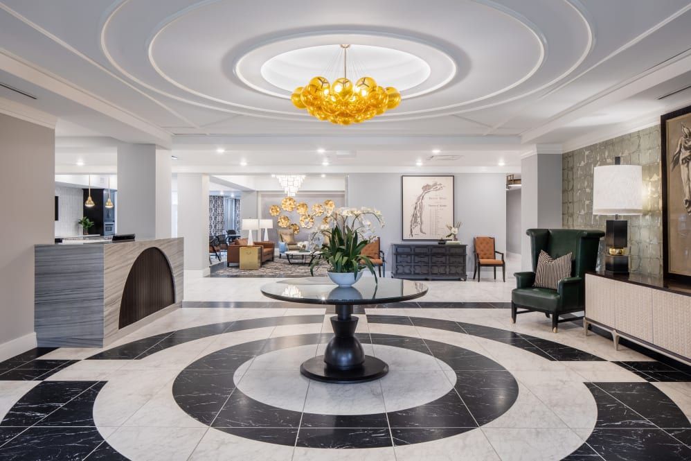 A luxurious hotel lobby featuring a modern chandelier and elegant seating area.