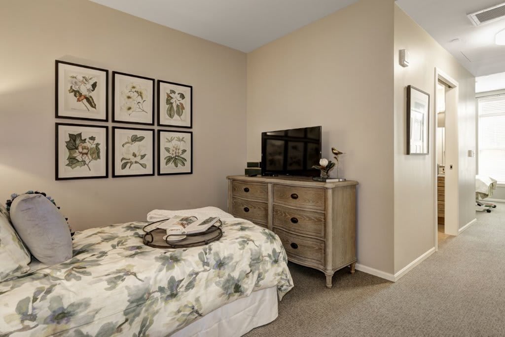 Cozy bedroom with a floral bedspread and a dresser topped with a TV.