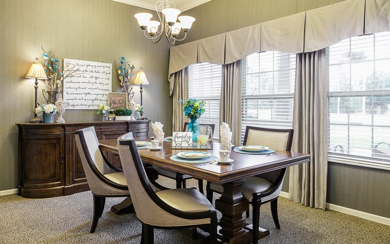 Elegantly decorated dining room with a wooden table set and upholstered chairs.