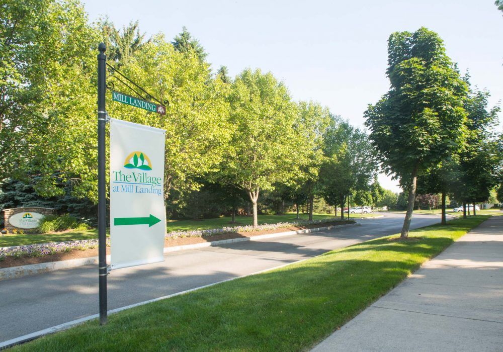 The entrance to a park with lush greenery and clear signage by the roadside.