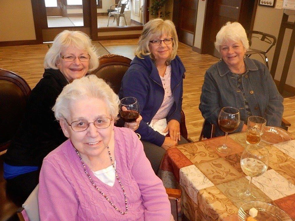 A group of elderly women smiling and enjoying a gathering indoors.