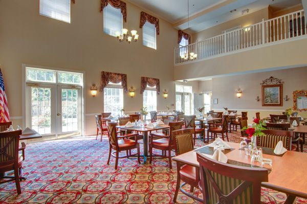A spacious dining room with neatly arranged tables and chairs, featuring large windows and elegant decor.