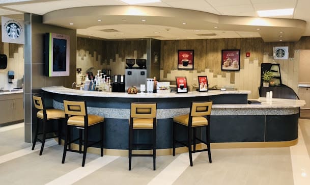 A modern cafe counter with bar stools and a selection of coffee equipment.