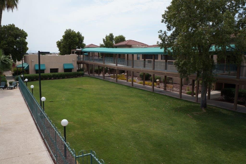 A view of a school courtyard with a well-maintained lawn and surrounding buildings.
