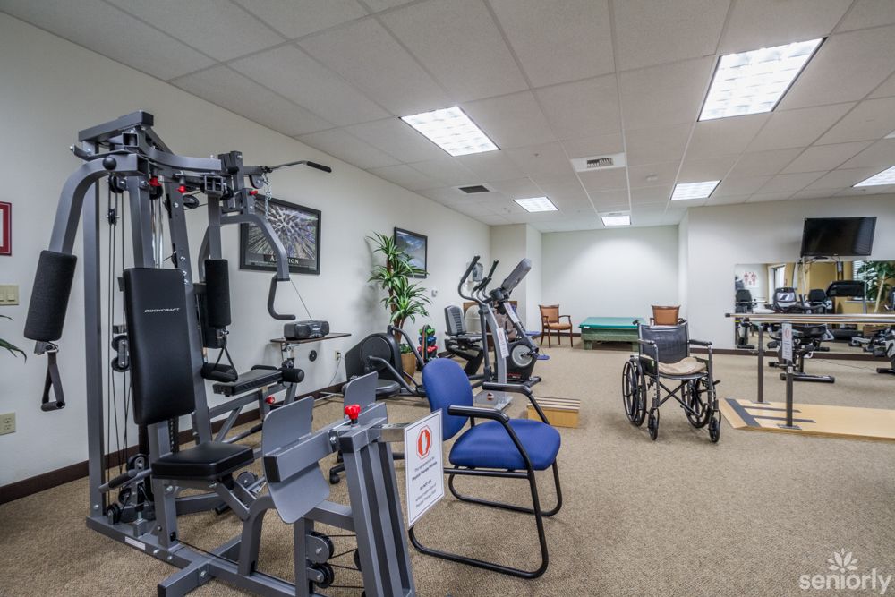 A well-equipped gym room featuring various fitness machines and a wheelchair accessible setup.