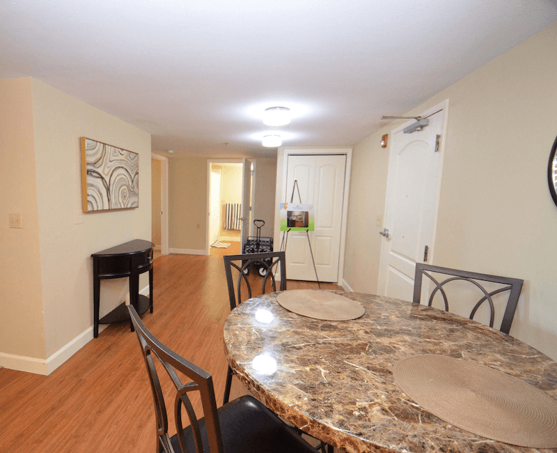 A modern dining room with a marble table and hardwood floors.
