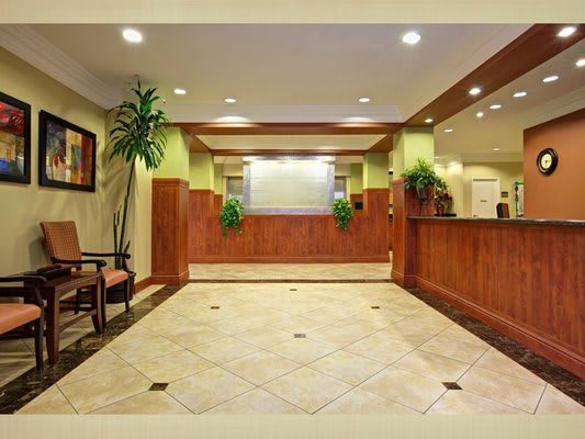 A spacious hotel lobby with a reception desk and seating area.
