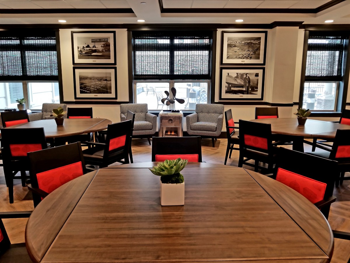 A modern dining area with wooden tables, red-accented chairs, and elegant decor.