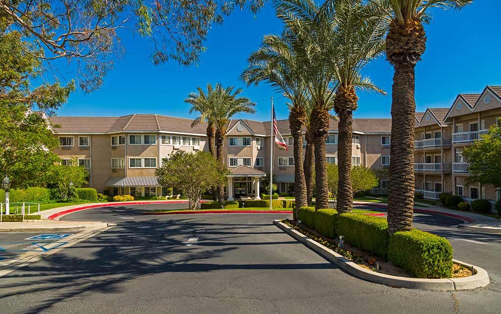 A residential building surrounded by palm trees on a sunny day.