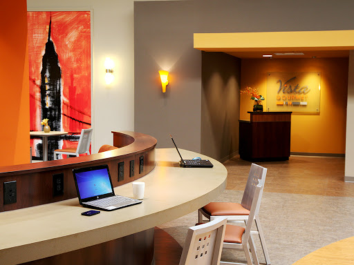 A modern lobby area with a reception desk, artwork on the wall, and workstations for guests.
