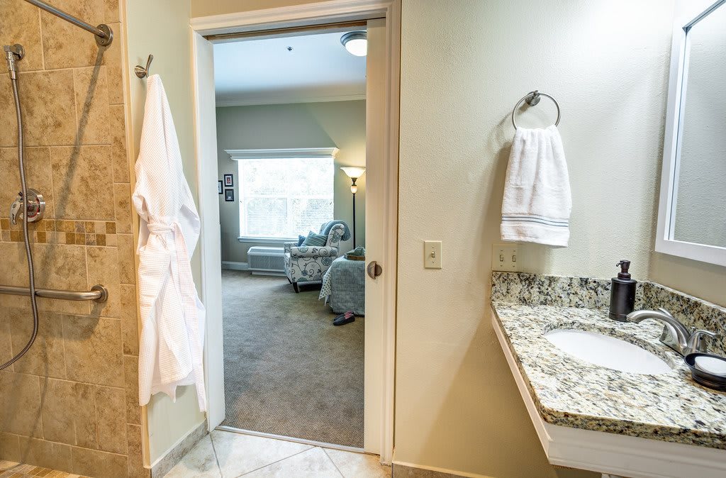 A bathroom with a view into a cozy, well-lit bedroom.