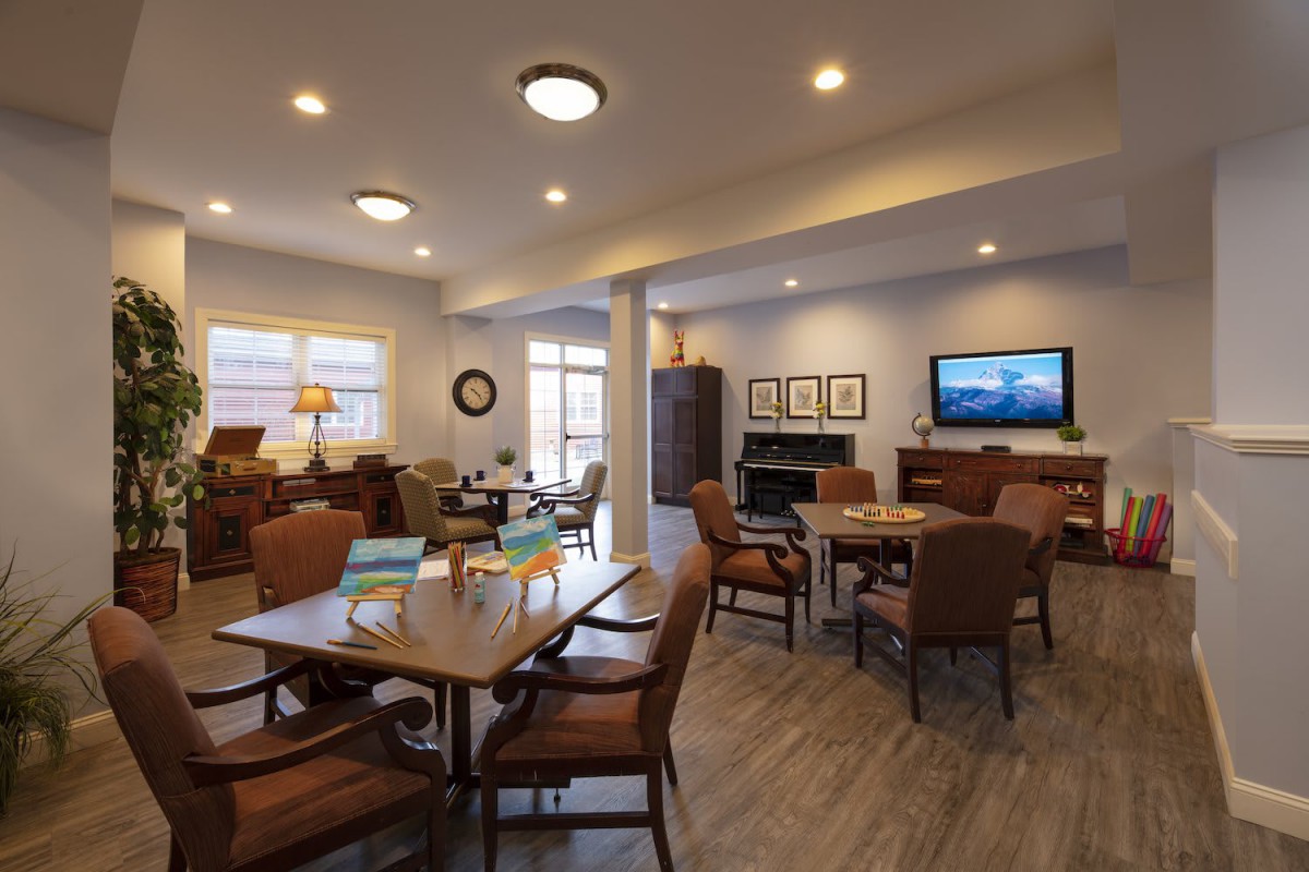 A cozy lounge area with tables, chairs, a television, and a fireplace.