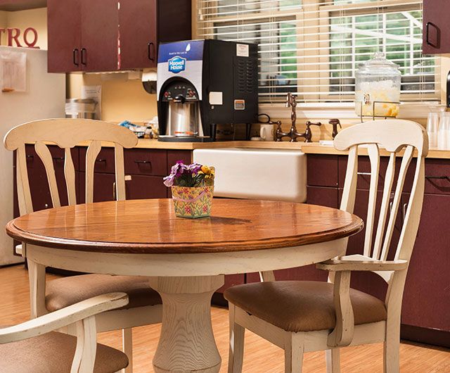 A cozy kitchen with a round dining table and chairs, featuring a coffee maker on the counter.