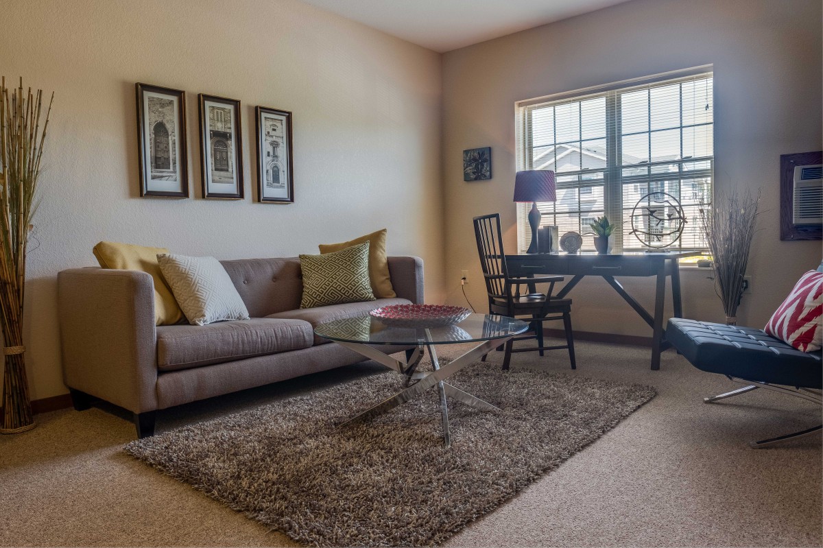 A cozy living room with a sofa, coffee table, and desk by the window.