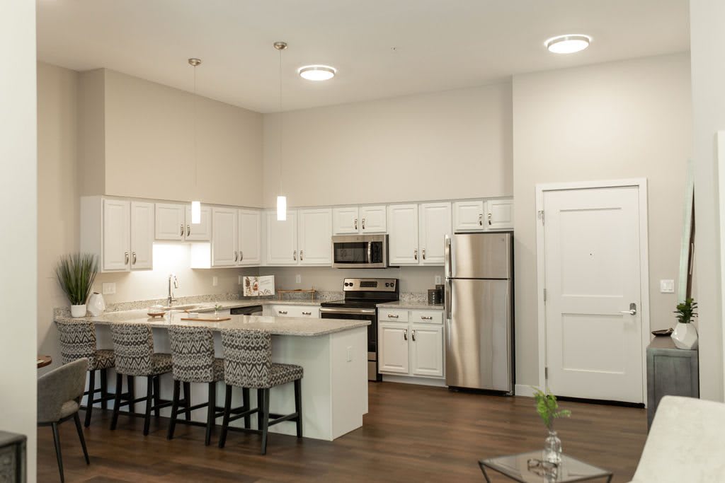 A modern kitchen with white cabinets, stainless steel appliances, and an island counter with bar stools.