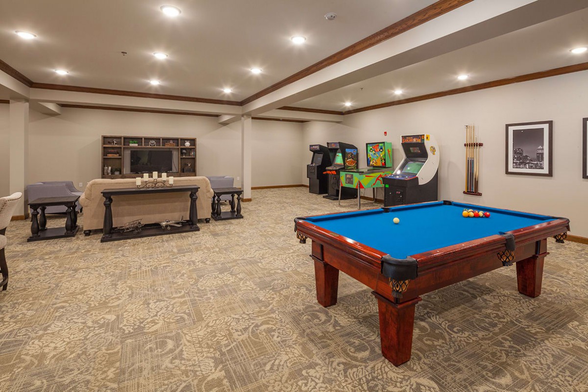 A spacious game room featuring a pool table and several arcade games.