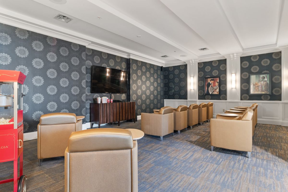 A modern lounge area with leather seating, a television, and decorative wallpaper.