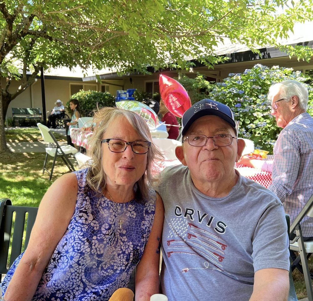 A couple sitting together in a garden setting during the daytime.