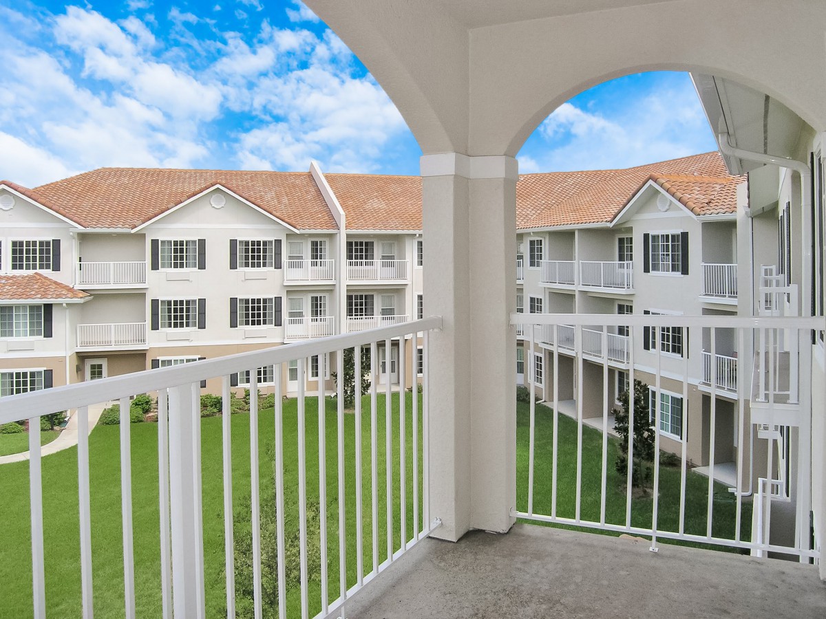 View from a balcony overlooking an apartment complex with a clear blue sky.