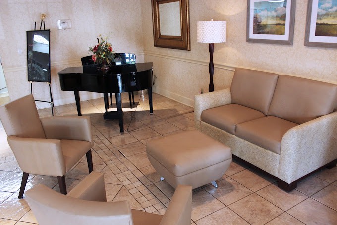 A cozy living room with a piano, sofas, and a lamp creating a welcoming atmosphere.