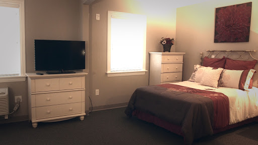 A cozy bedroom featuring a bed, dresser, and television.