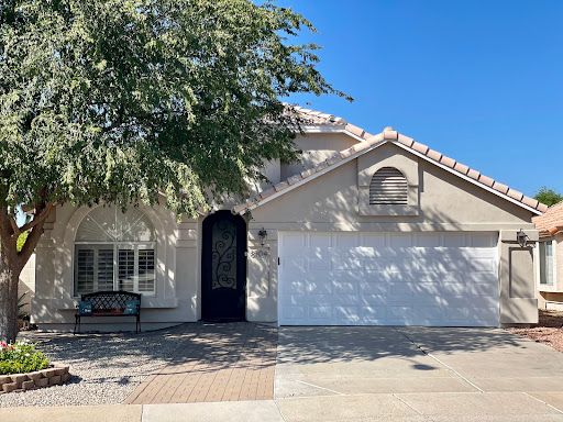A charming single-family home with a garage and a welcoming front yard on a bright sunny day.