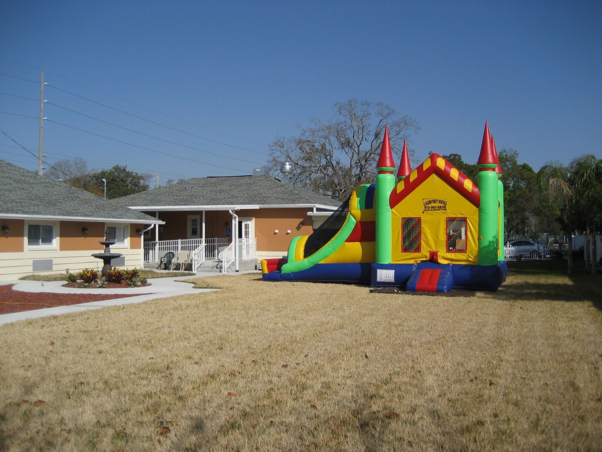 A colorful inflatable bounce house set up on a lawn in front of a residential home.