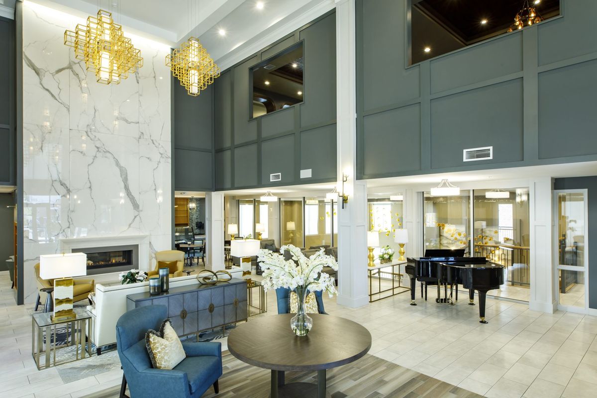 A modern and luxurious lobby featuring elegant seating, a grand piano, and stylish chandeliers.