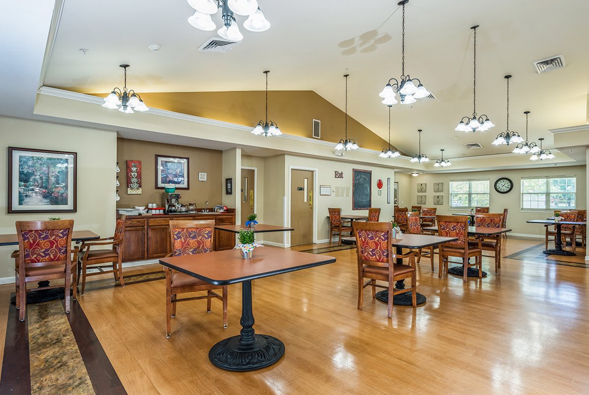 A spacious and well-lit dining area with wooden floors, tables, and chairs.