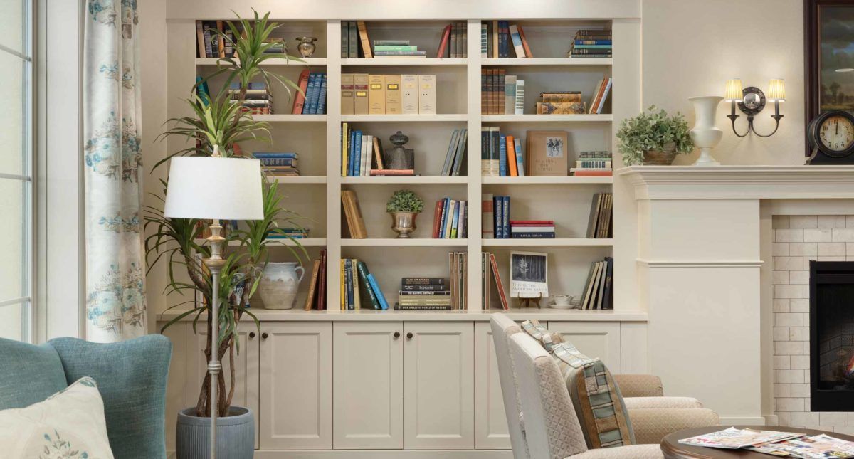 A cozy living room with a large bookshelf filled with books and decorative items.