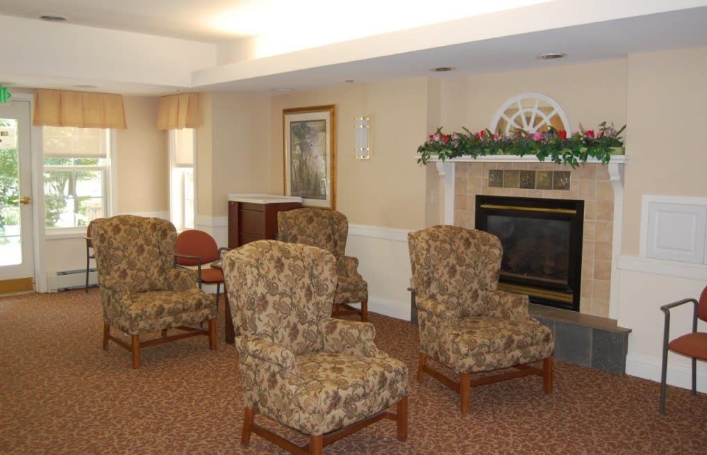 A cozy living room with patterned chairs arranged around a fireplace.