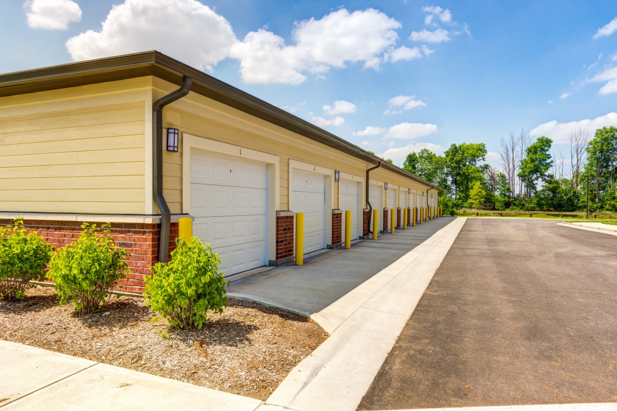 Row of outdoor storage units with a paved driveway on a sunny day.