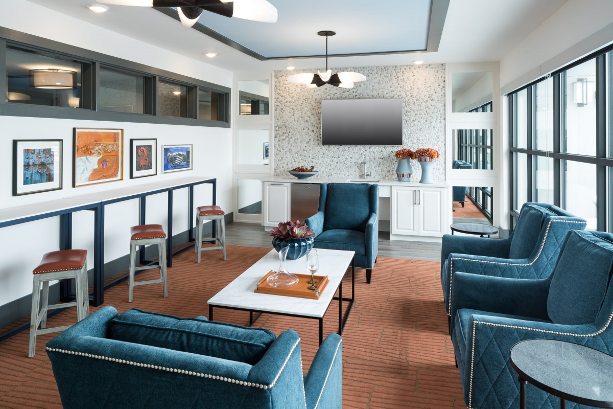 A modern living room featuring cozy blue chairs, a wall-mounted TV, and contemporary artwork.