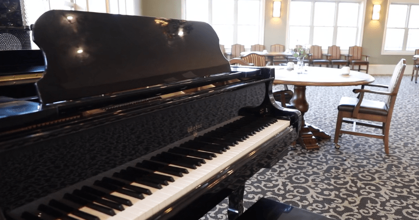 A black piano in a well-lit room with elegant furniture.
