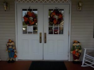Front doors decorated with autumn wreaths and scarecrows.