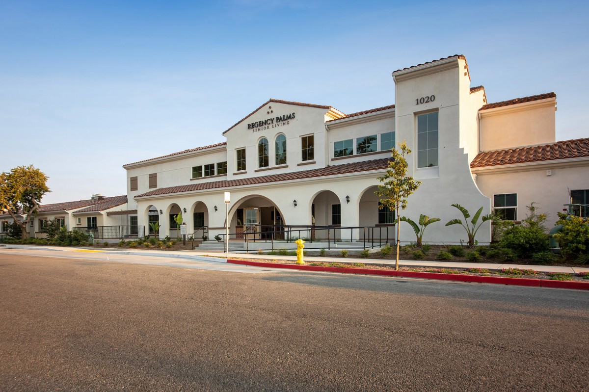 A modern building with arched windows and a clean facade, situated along a quiet street.