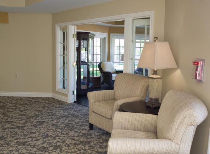 A cozy living room with armchairs, a lamp, and a cabinet showcasing a warm and inviting interior.