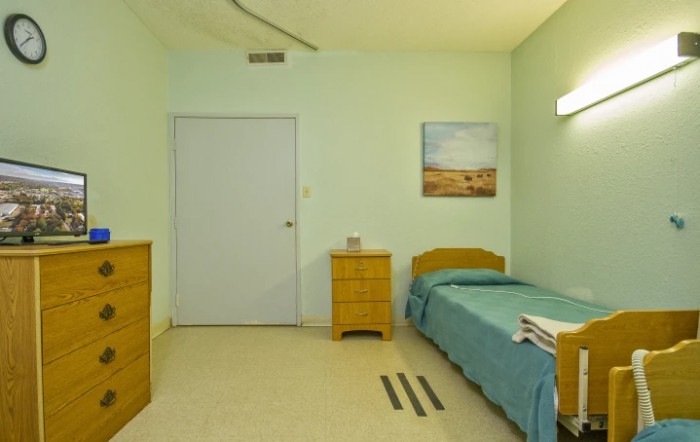 A minimalist bedroom with a single bed, a small dresser, and simple decor.
