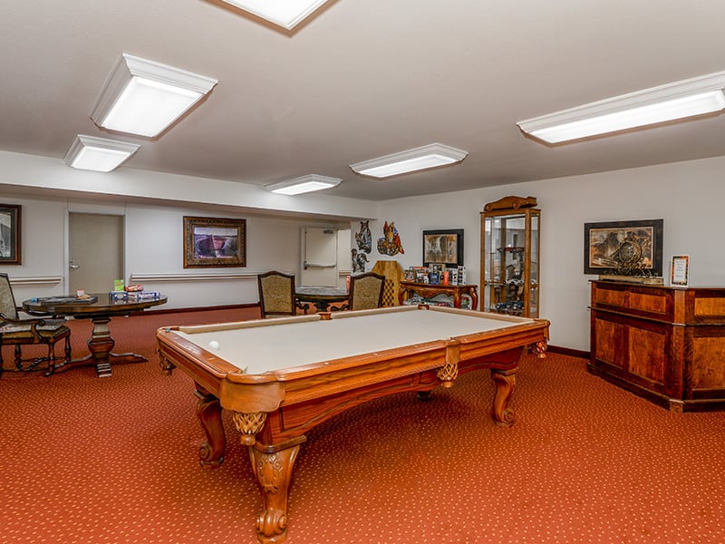 A spacious recreation room featuring a billiards table and classic interior decor.