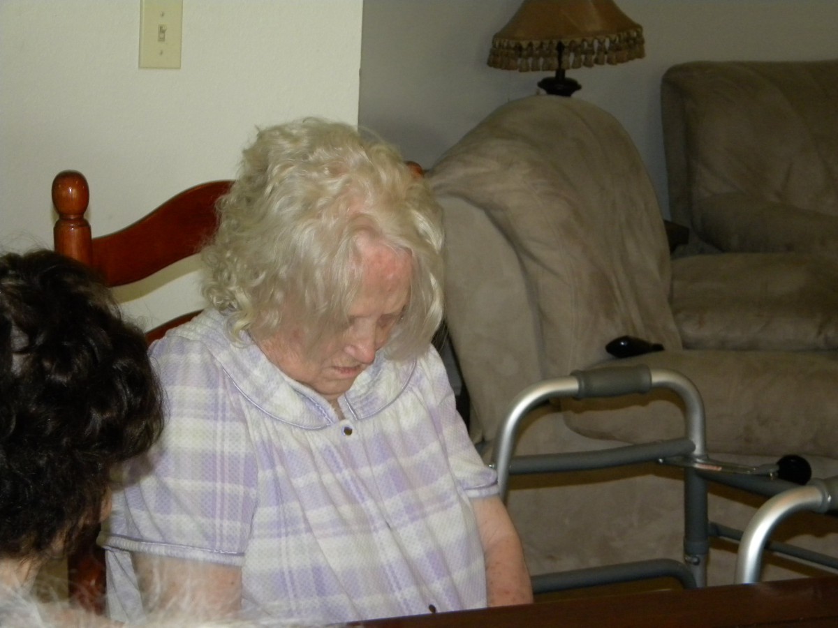 An elderly woman sitting with a walker in a home setting.
