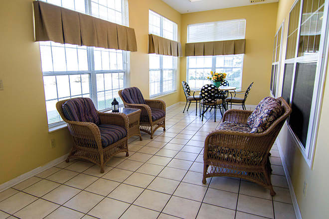 A bright sunroom with wicker furniture and large windows.