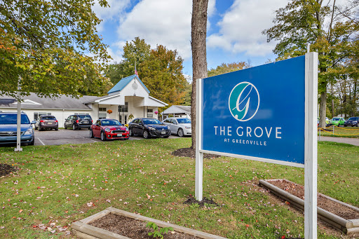 Exterior view of The Grove facility with a clear sign and surrounding landscape.